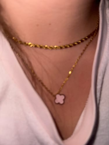 Nahaufnahme: Ein Kunde trägt die Baby Pink Clover Kette, kombiniert mit einer anderen Goldkette.