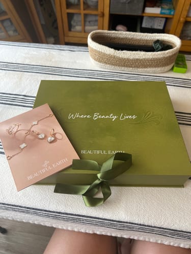 Customer's green 12 pcs Spring Box Packaging, closed with a ribbon, resting on a striped tablecloth.