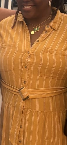 Reviewer wearing the Jade Butterfly Necklace, layered with another gold necklace on a striped shirt.