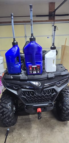 Customer's three utility jugs in different sizes, two blue and one white, on an ATV.