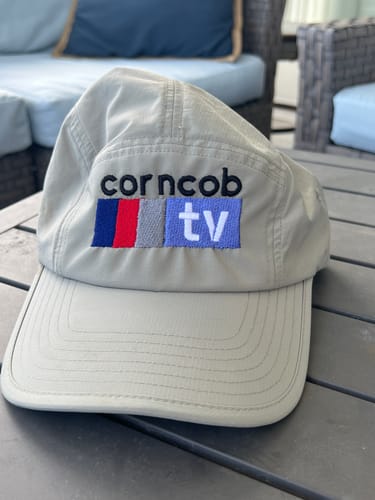 Customer's custom-embroidered Big Camp Hat Ripstop in a light gray color, sitting on an outdoor table.