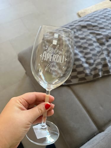 Ein Kunde hält das Leonardo Weinglas mit der Gravur „Holy Aperoli Nina“ in der Hand.