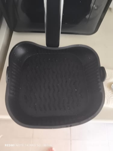Clientul prezintă tava de protecție neagră din silicon, așezată în coșul unei friteuze cu aer cald.