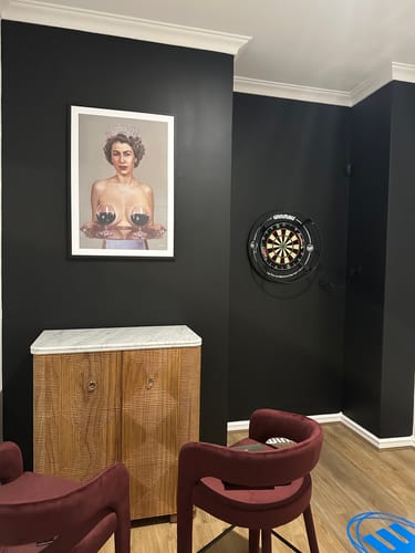 Customer's framed print with a White Gallery Mat Board, displayed in a dark-walled darts room.