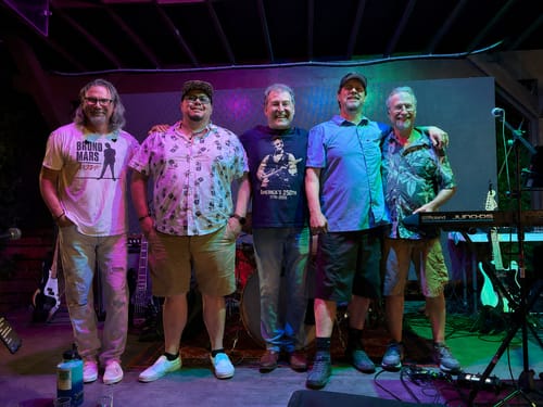 Reviewer wearing the Rushmore Tour 250 T-Shirt on stage with his bandmates.