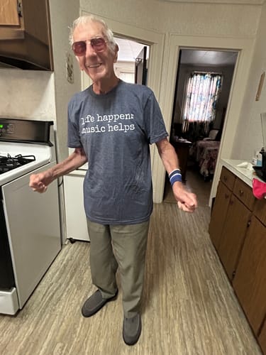 A happy reviewer models the blue Life Happens T-Shirt in a kitchen.