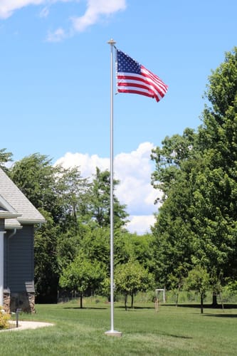 Customer's tall Ultra Heavy-Duty Home Flagpole with an American flag flying in a grassy yard.