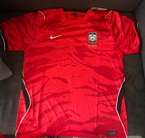 Maillot rouge Corée du Sud Domicile 2026 avec un motif tigré, posé à plat.