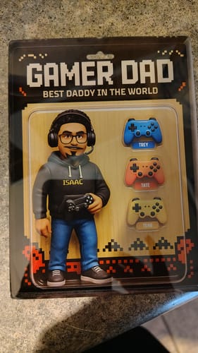 Customer's personalized Gamer Dad action figure plaque in its packaging, showing the custom figure 'Isaac' and three named controllers.