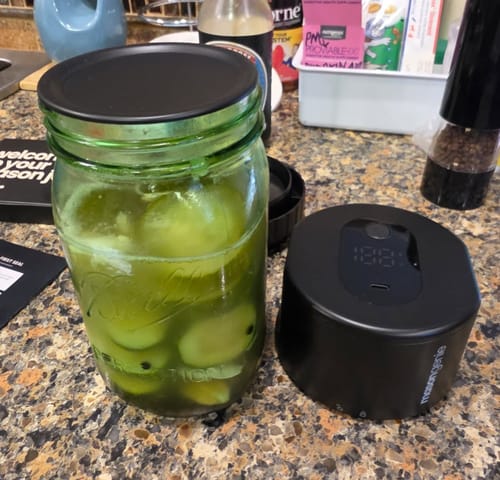 Customer's Mason Genie device on a countertop next to a large, sealed mason jar of fermented vegetables.