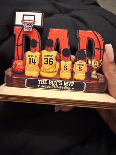 Customer holds the 'Basketball Dad' personalized wooden plaque, showing a family in jerseys.