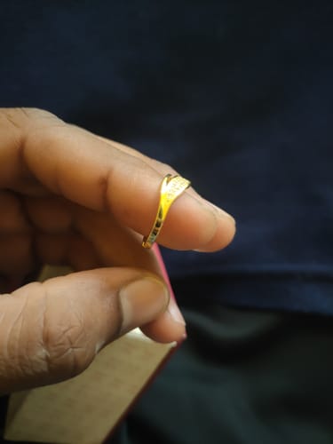 Customer holding the gold-plated wave ring on their finger, showing its studded design.