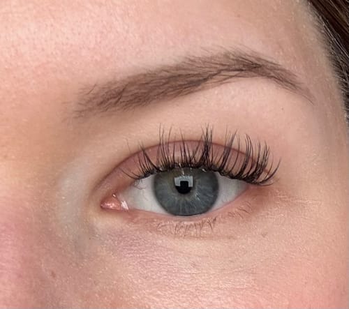 Nahaufnahme des Auges einer Kundin mit angebrachten, langen Flaw Lash Wimpernverlängerungen.