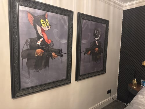 Customer's framed Catface art print hung on a wall next to another similar artwork.