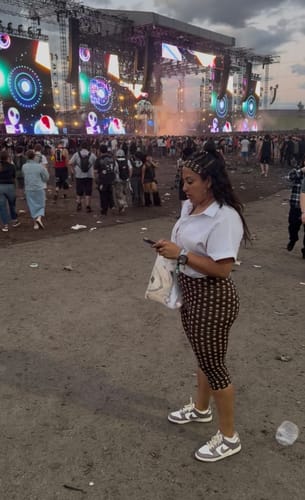 Reviewer standing at an outdoor festival wearing the Naked Print Capri Legging with a white shirt.