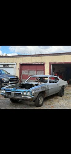 A customer's vintage muscle car project, shown partially disassembled in front of a garage.