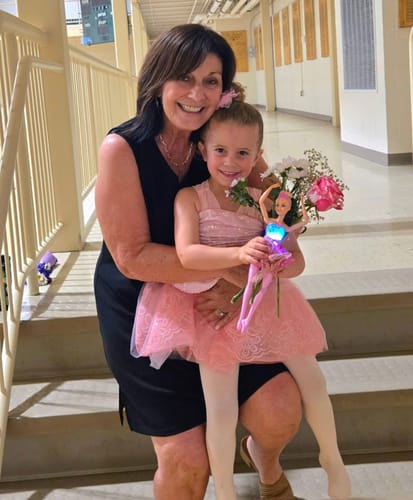 A happy reviewer of the Seranova Micro Infusion System smiling in a photo with a child in a ballet costume.