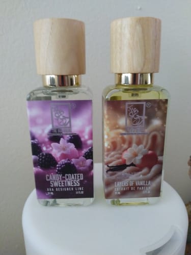 Customer photo of a Dua Layers Of Vanilla bottle with a light wood cap beside another fragrance