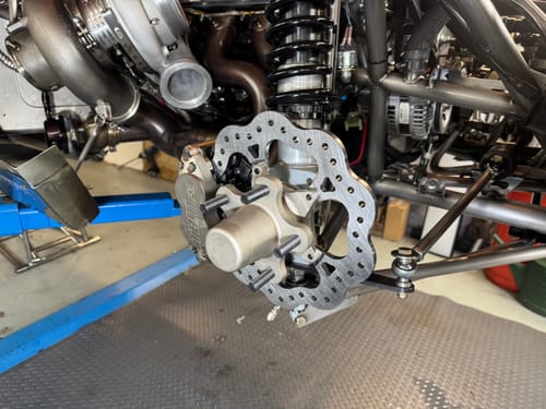 Close-up of a customer's Strange F3 4 Piston Caliper and steel rotor assembly installed on a race car.
