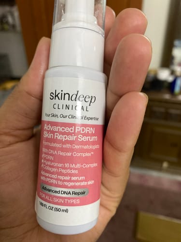 A customer's hand holding the white and pink bottle of Advanced PDRN Skin Repair Serum.