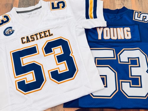 Customer's two custom football jerseys, one white and one blue, showing the stitched names and number 53.