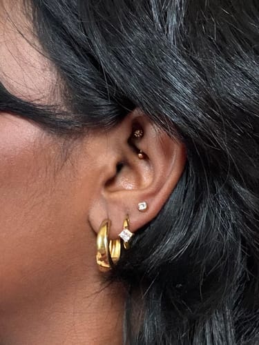 Customer wearing the Roselle Crystal Huggies in an ear stack with a thicker gold hoop and studs.