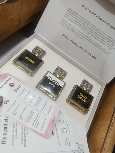 Reviewer unboxing the OUD Supreme BUNDLE, revealing three elegant perfume bottles in a white presentation box.