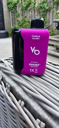 A customer's black and purple Ghost Galaxy vape bar in the 'Purple Slush' flavor, standing on a wicker surface outdoors.