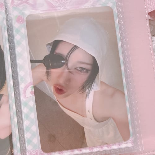 Reviewer's XLOV "I,God" photocard in a sleeve, showing a person in a white hat holding sunglasses over one eye.