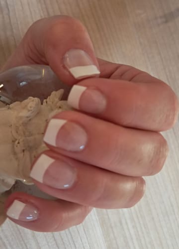Nahaufnahme der Nägel einer Kundin, die die 'Classy French' UV-Gel-Maniküre trägt.