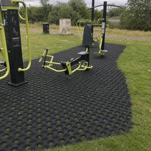Reviewer's rubber grass mats installed on a lawn, providing a sturdy base for outdoor gym equipment.