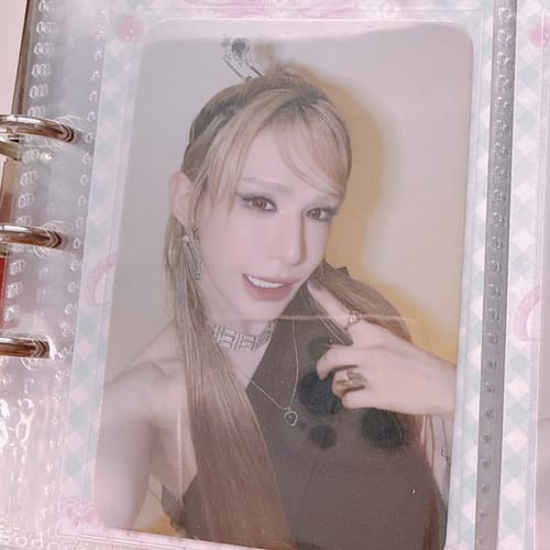 Customer's XLOV "I,God" Fansign Event Photocard featuring a person with blonde hair, held in a clear protective binder sleeve.