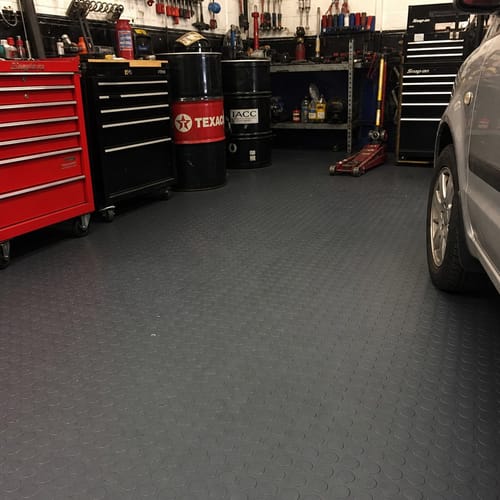 Customer's dark grey Studded Dot Penny Rubber Flooring installed in a car repair shop, with tool chests and a car on it.