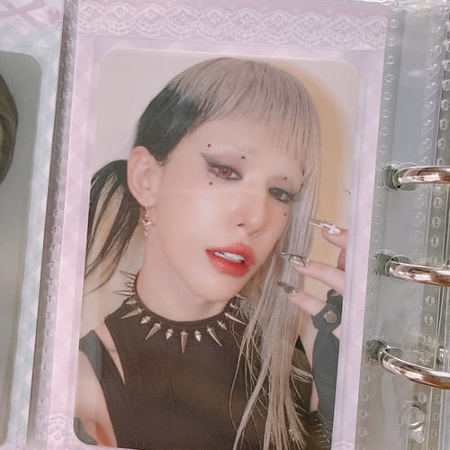 Customer's XLOV "I,God" photocard in a protective sleeve, featuring a person with dramatic makeup and split-dye hair.
