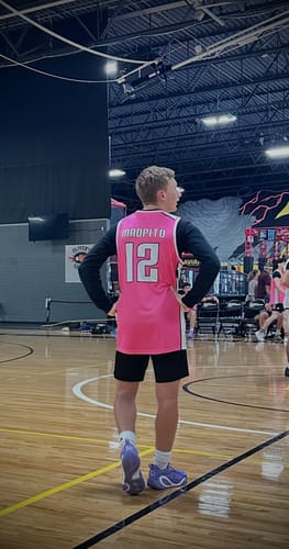 Customer on a basketball court wearing the custom pink and white basketball jersey, seen from the back.