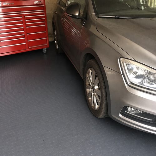 Customer's dark grey Studded Dot Rubber Flooring installed in a garage, with a car parked on it next to a red tool chest.