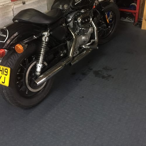 Customer shows their black motorcycle parked on the dark grey Studded Dot Penny Rubber Flooring in a garage, with oil spots visible.