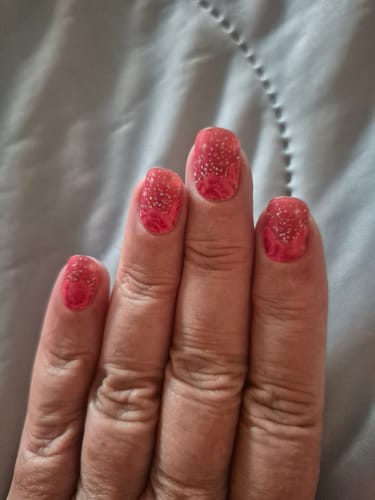 Nahaufnahme der Hand einer Kundenrezensentin mit aufgetragenen 'Glitter Rose Ombré' UV-Gel-Nagelfolien.
