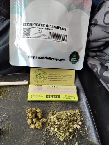 A reviewer's bag of ZAZA Maui Wowie Littles shown with the small buds and ground flower on a rolling tray.