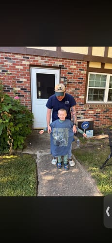 A customer's photo of a child holding up the large blue personalized shirt with his dad standing behind him.