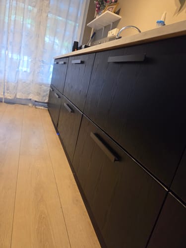 Nærbilde av en kundes kjøkkenskuffer dekket med Treverk sort matt kontaktplast, som viser trestrukturen.