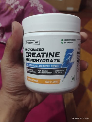 Customer holding a white tub of Wellcore Micronised Creatine Monohydrate in the Tropical Tango flavor.