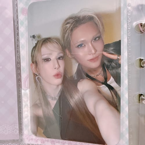 Reviewer's XLOV "I,God" photocard featuring two people, displayed in a clear binder sleeve.