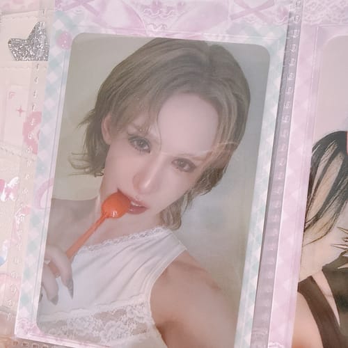 Customer's XLOV "I,God" photocard featuring a person in a white top holding an orange spoon to their lips.