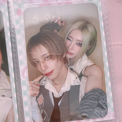 Customer's XLOV "I,God" pre-order photocard showing two people posing together inside a protective sleeve.
