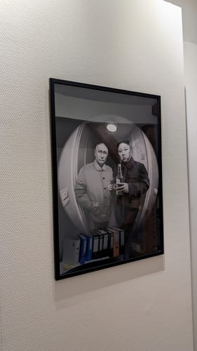 Customer's 'The Good Stuff' art print in a black frame, hanging on a white wall. The print shows two men in a fisheye view.