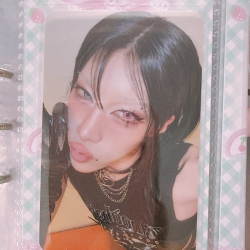 Customer's XLOV "I,God" Hellolive Showcase Event Photocard showing a close-up of a person with dramatic makeup in a binder sleeve.