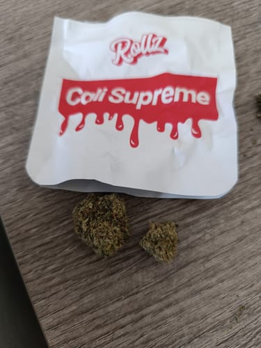 Customer's two dried buds of CALI SUPREME THCA Flower displayed with the product's white and red packaging.