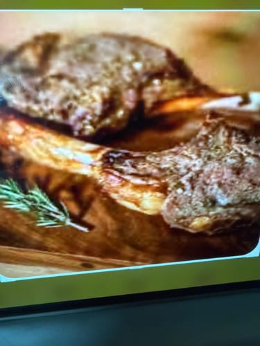 Close-up: Reviewer's juicy, cooked Halal Lamb Tomahawk steaks on a wooden board.