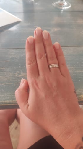 Die Hand einer Kundin mit einer dezenten Maniküre durch die 'Rosé Chrome' UV-Nagelfolien.